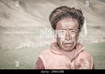 Dolpo, Nepal, um Juni 2012: Alte gebürtige Frau mit braunen Dreadlocks trägt oranges Hemd in Dolpo, Nepal. Dokumentarisches Editorial Stockfoto