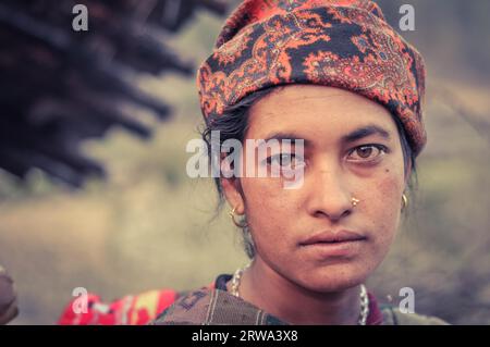 Dolpo, Nepal, um Mai 2012: Die gebürtige Frau mit Piercing und Ohrringen trägt ein oranges Kopftuch mit braunen Augen in Dolpo, Nepal. Dokumentarisches Editorial Stockfoto