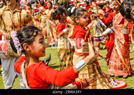 Guwahati, Assam, um April 2012: Tanzende Mädchen in rot-gelbem Sari mit rotem Punkt auf der Stirn lächeln während der Performance im traditionellen Bihu Stockfoto