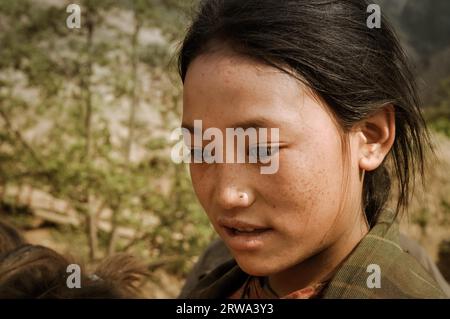 Dolpo, Nepal, um Mai 2012: Junges schwarzhaariges Mädchen mit braunen Augen schaut nach unten und spricht in Dolpo, Nepal. Dokumentarisches Editorial Stockfoto