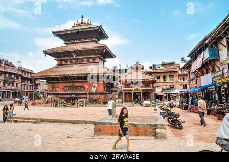 Bhaktapur, Nepal, um Juni 2012: Menschen gehen durch den Marktplatz mit dem hohen alten Gebäude in der Mitte des Platzes in Bhaktapur, Nepal. Dokumentarfilm Stockfoto