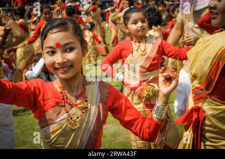 Guwahati, Assam, um April 2012: Junge gebürtige Frau in rot-gelbem Sari lächelt und tanzt während der Vorstellung auf dem traditionellen Bihu-Festival in Stockfoto