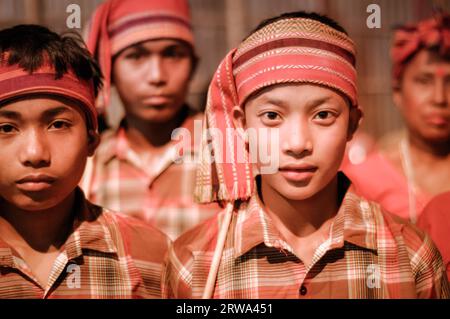 Guwahati, Assam, um April 2012: Junge einheimische Jungen in orangen Kostümen und mit Stirnband schauen auf dem Bihu-Festival in Guwahati, Assam, auf Fotokamera. Stockfoto