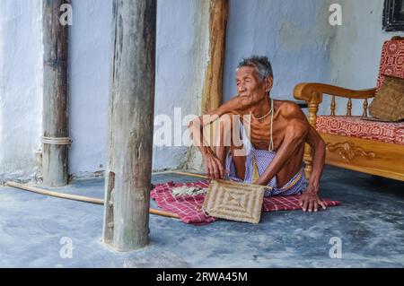 Srimongal, Bangladesch, um Juli 2012: Der alte dünne Mann sitzt auf einer karierten Decke auf dem Boden und schaut in Srimongal, Bangladesch, nach links. Dokumentarfilm Stockfoto