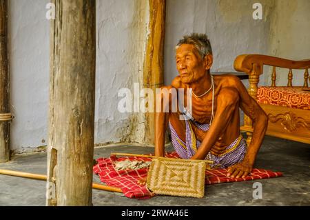 Srimongal, Bangladesch, um Juli 2012: Foto eines alten dünnen Mannes, der auf karierter Decke auf dem Boden in Srimongal, Bangladesch sitzt. Dokumentarisches Editorial Stockfoto