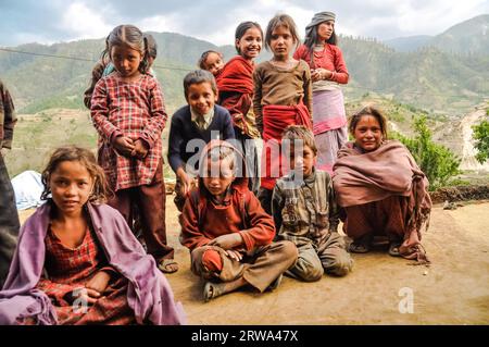 Dolpo, Nepal, um Juni 2012: Eine Gruppe junger Mädchen und Jungen in farbenfroher Kleidung sitzt auf dem Boden oder steht und schaut neugierig im Hintergrund mit Stockfoto