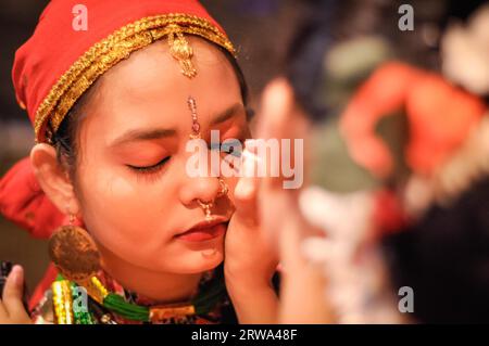 Guwahati, Assam, um April 2012: Junge einheimische Mädchen mit rotem Kopftuch und Ohrringen bekommt ihr Auge beim Bihu Festival in Guwahati mit Augenstift gesäumt Stockfoto