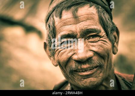 Dolpo, Nepal, um Mai 2012: Foto eines alten, faltigen Mannes mit grauem Haar und Schnurrbart, der in Dolpo, Nepal, schön mit der Fotokamera lächelt. Dokumentarfilm Stockfoto