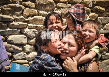 Dolpo, Nepal, um Juni 2012: Kleine Kinder umarmen ihre Mutter und lächeln freudig vor der Fotokamera in Dolpo, Nepal. Dokumentarisches Editorial Stockfoto