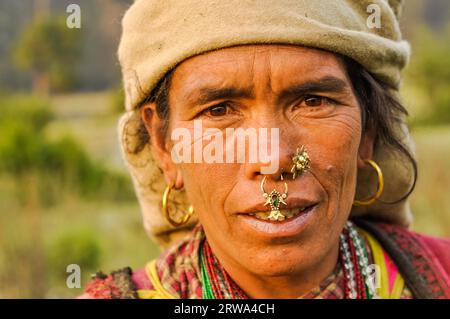 Dolpo, Nepal, um Mai 2012: Die gebürtige Frau mit braunem Kopftuch hat große Ohrringe und Piercings in der Nase mit braunen Augen in Dolpo, Nepal. Stockfoto