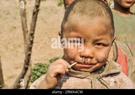 Dolpo, Nepal, um Mai 2012: Junge mit Dreck im Gesicht hat Lutscher im Mund in Dolpo, Nepal. Dokumentarisches Editorial Stockfoto