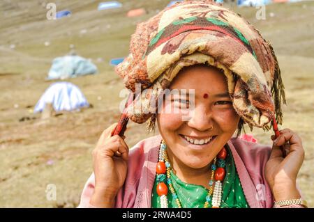 Dolpo, Nepal, ca. Mai 2012: Foto einer lächelnden Frau mit einem Schal auf dem Kopf in einem grünen gepunkteten Hemd und einem pinken Sweatshirt mit Perlen Stockfoto