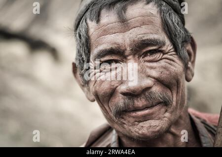 Dolpo, Nepal, um Mai 2012: Ein alter, faltiger Mann mit grauem Haar und Schnurrbart lächelt schön vor der Fotokamera in Dolpo, Nepal. Dokumentarisches Editorial Stockfoto