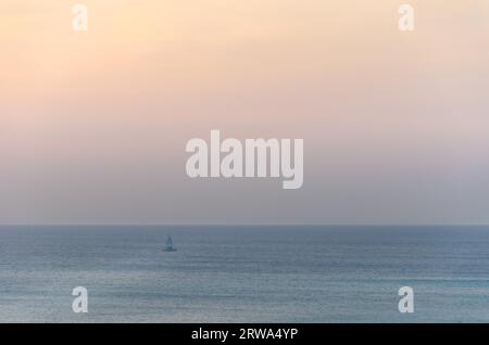 Segelboote auf See, die unter dem Sonnenuntergang navigieren. Das Bild wurde von Palm Beach in Aruba, im Karibischen Meer, aufgenommen Stockfoto