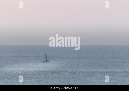 Segelboote auf See, die unter dem Sonnenuntergang navigieren. Das Bild wurde von Palm Beach in Aruba, im Karibischen Meer, aufgenommen Stockfoto