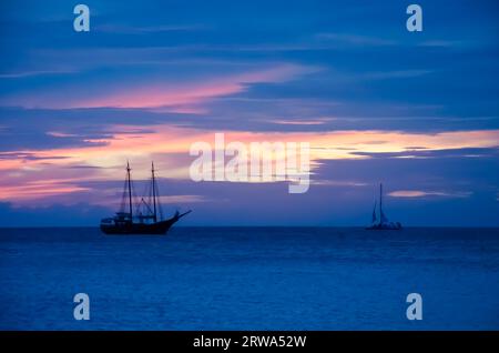 Piratensegelboot auf See, das in Richtung Sonnenuntergang navigiert. Das Bild wurde von Palm Beach in Aruba, im Karibischen Meer, aufgenommen Stockfoto