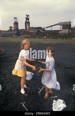 Bergleute streiken 1980er Jahre in Großbritannien. Shirebrook Colliery Derbyshire. Die markanten Bergleute suchen zwei junge Mädchen, die ihrer Familie im Abfallgebiet der verdorbenen Spitze helfen, nach Kohle. Freie Kohle war ein Vorteil, den alle Bergarbeiter genossen. Die Kohle wurde für die Hausheizung usw. verwendet Die arbeitenden Bergleute, die als Schorf bekannt waren, erhielten immer noch ihre kostenlose Kohleversorgung. 1984 UK HOMER SYKES Stockfoto