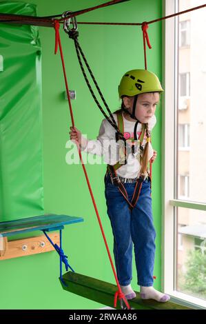 Kinderseilbahn im Spielzimmer passiert das kleine Mädchen die Seilbahn, die aktive und körperliche Entwicklung des Kindes. Stockfoto