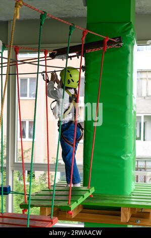 Kinderseilbahn im Spielzimmer passiert das kleine Mädchen die Seilbahn, die aktive und körperliche Entwicklung des Kindes. Stockfoto