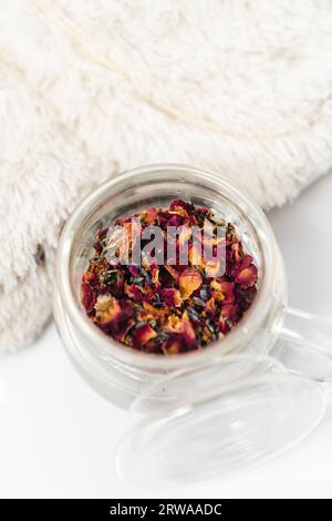 Eine Teekanne aus Glas mit Rosentee und weißen Hausschuhen Stockfoto