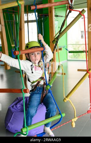 Aktive und körperliche Entwicklung des Kindes, das Mädchen passiert die Seilbahn im Spielzimmer. Stockfoto