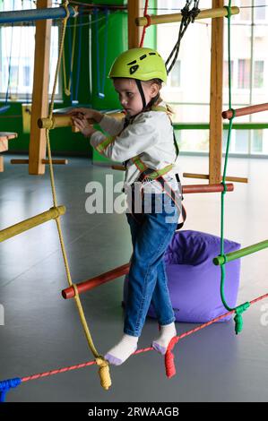 Aktive und körperliche Entwicklung des Kindes, das Mädchen passiert die Seilbahn im Spielzimmer. Stockfoto