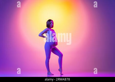 Sportliche schwangere Frau vor Farbhintergrund Stockfoto