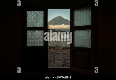 Blick durch eine offene Retro-Tür auf den Vulkan de Agua, der über der Stadt Antigua, Guatemala, aufragt Stockfoto