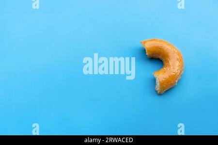 Gebissener glasierter Donut isoliert auf blauem Hintergrund. Nach einigen Bearbeitungen. Stockfoto