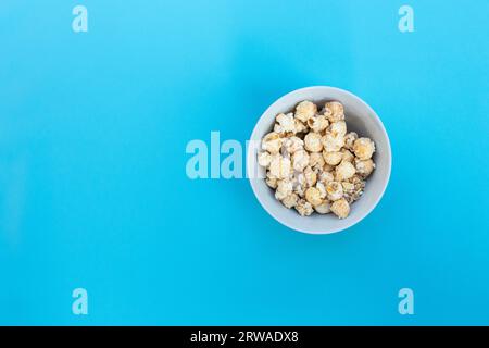 Popcorn in Schale isoliert auf blauem Hintergrund, nach einigen Bearbeitungen. Stockfoto