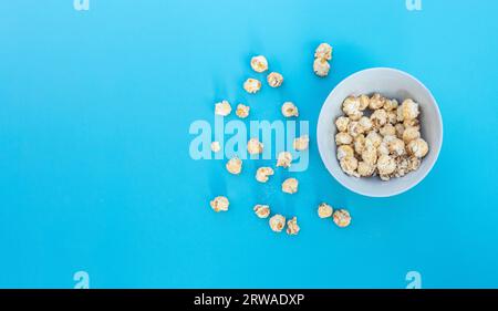 Popcorn in Schale isoliert auf blauem Hintergrund, nach einigen Bearbeitungen. Stockfoto