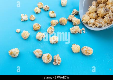 Popcorn in Schale isoliert auf blauem Hintergrund, nach einigen Bearbeitungen. Stockfoto