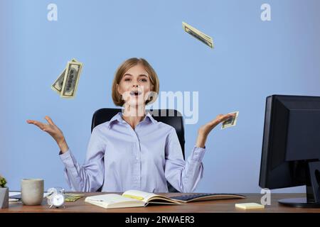Geschäftsfrau, die Geld wirft, während sie auf dem Stuhl am Schreibtisch sitzt. Stockfoto