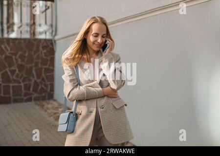 Lächelnde Frau, die auf der Straße steht und auf ihrem Handy spricht, Weißrussland Stockfoto