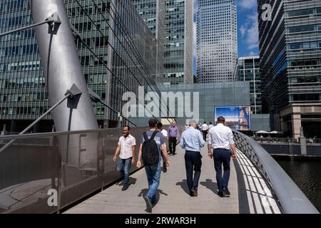 Menschen und Arbeiter, die am 15. August 2023 in London die South Quay Fußgängerbrücke im Herzen des Finanzdistrikts Canary Wharf überqueren. Canary Wharf ist ein Gebiet in der Nähe der Isle of Dogs im London Borough of Tower Hamlets und wird von der Greater London Authority als Teil des zentralen Londoner Geschäftsviertels definiert. Zusammen mit der City of London ist sie eines der wichtigsten Finanzzentren in Großbritannien und der Welt und beherbergt viele Hochhäuser. In den letzten Jahren hat sich die Arbeitsweise von Büro- zu Hybrid- und Remotearbeit gewandelt Stockfoto