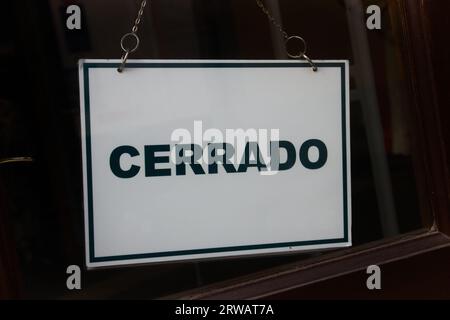 Nahaufnahme eines Schildes mit dem Wort Close auf spanisch „cerrado“, das an der Tür eines Unternehmens hagelt Stockfoto