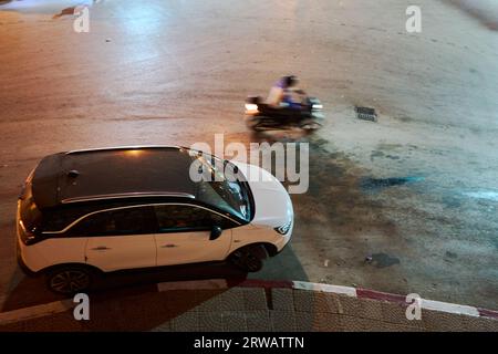 Verschwommenes Motorrad neben einem Auto bei Nacht Stockfoto