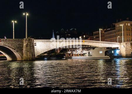 Ein Boot auf dem Bateaux Lyonnais führt nachts unter der Pont Bonaparte in Lyon, Rhonealpen, Frankreich. Stockfoto