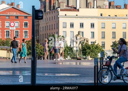 Touristen versammeln sich neben der Statue „das Gewicht eines selbst“ am Ufer der Saone in Lyon, Frankreich. Stockfoto