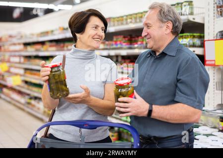 Ein älteres Ehepaar, das sich zusammen in der Supermarktregion die Gurkenkonserven ausgesucht hat Stockfoto