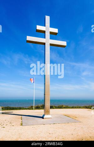 Großes Kreuz von Lothringen vor der Flagge von Free France, das 1990 am Juno Beach errichtet wurde, um an die Rückkehr von General de Gaulle nach Frankreich im Jahr 1944 zu erinnern. Stockfoto