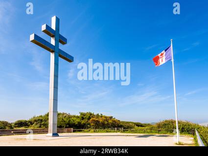 Großes Kreuz von Lothringen vor der Flagge von Free France, das 1990 am Juno Beach errichtet wurde, um an die Rückkehr von General de Gaulle nach Frankreich im Jahr 1944 zu erinnern. Stockfoto