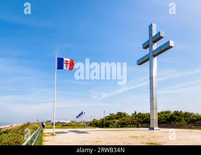 Großes Kreuz von Lothringen vor der Flagge von Free France, das 1990 am Juno Beach errichtet wurde, um an die Rückkehr von General de Gaulle nach Frankreich im Jahr 1944 zu erinnern. Stockfoto