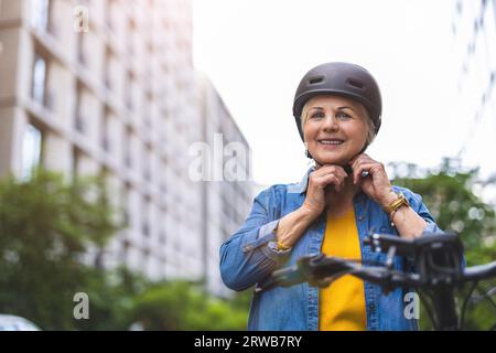 Porträt einer älteren Frau, die Helm trägt, während sie Fahrrad fährt in der Stadt Stockfoto