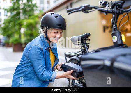 Reife Frau wechselt Batterie auf Elektrofahrrad Stockfoto