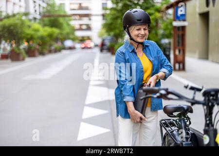 Reife Frau wechselt Batterie auf Elektrofahrrad Stockfoto