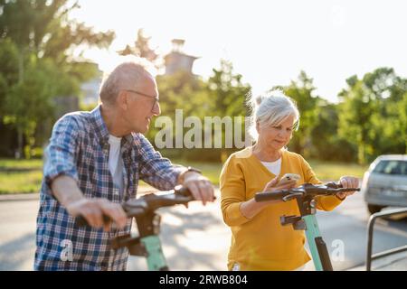 Ein älteres Paar, das in der Stadt Elektroroller fährt Stockfoto