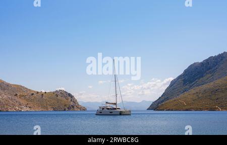 Symi Island, Griechenland. Griechenland Inseln Urlaub von Rhodos in der Ägäis. Große schöne Yacht in der Bucht in der Nähe des Dorfes Pedi, in der Nähe von Symi. Hintergrund der Urlaubsreise. Stockfoto