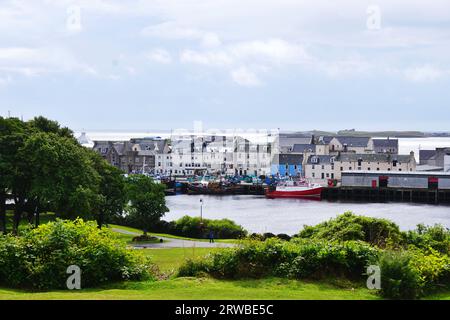 Blick über den geschützten Stornoway Hafen mit den Gebäuden in der Innenstadt und das Meer dahinter von den sanften Landschaftsgärten von Lews Castle, Isle of Lewis Stockfoto