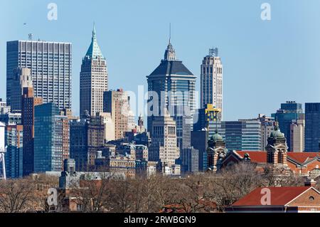 Ellis Island vom Liberty State Park, New Jersey: Die Skyline von New York City ragt hinter dem Hauptgebäude (heute Museum). Stockfoto